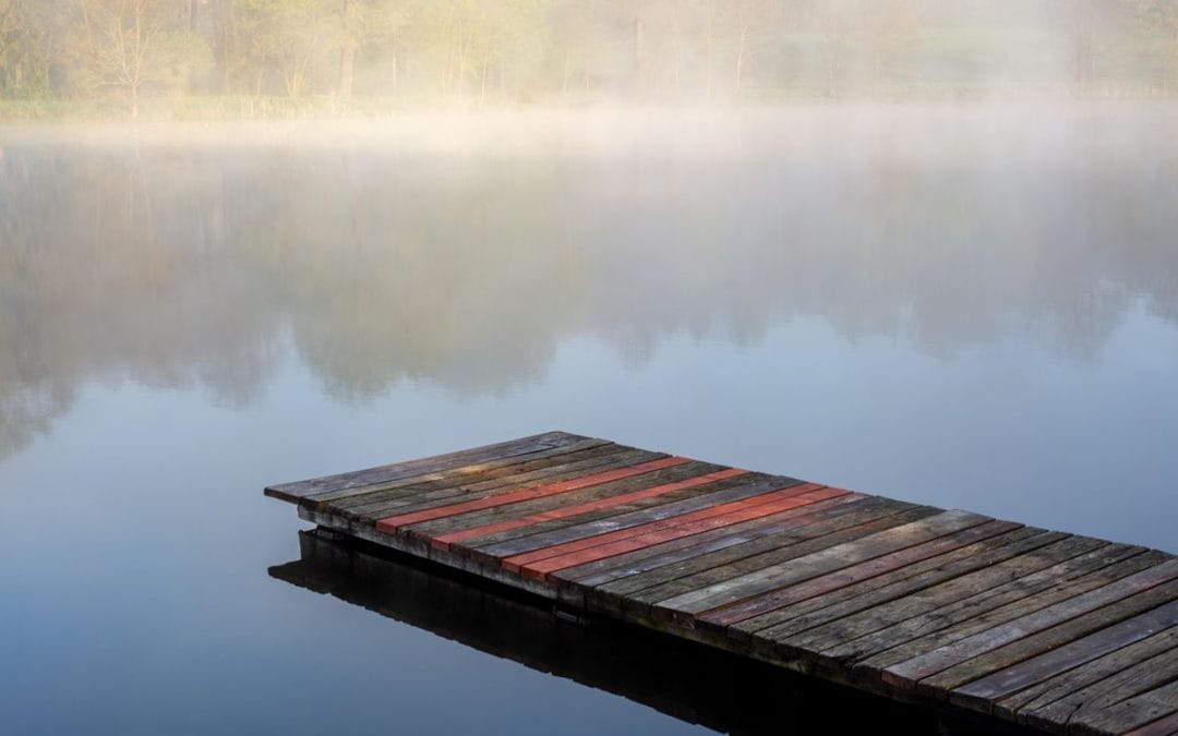 Wooden dock on a calm lake in morning mist